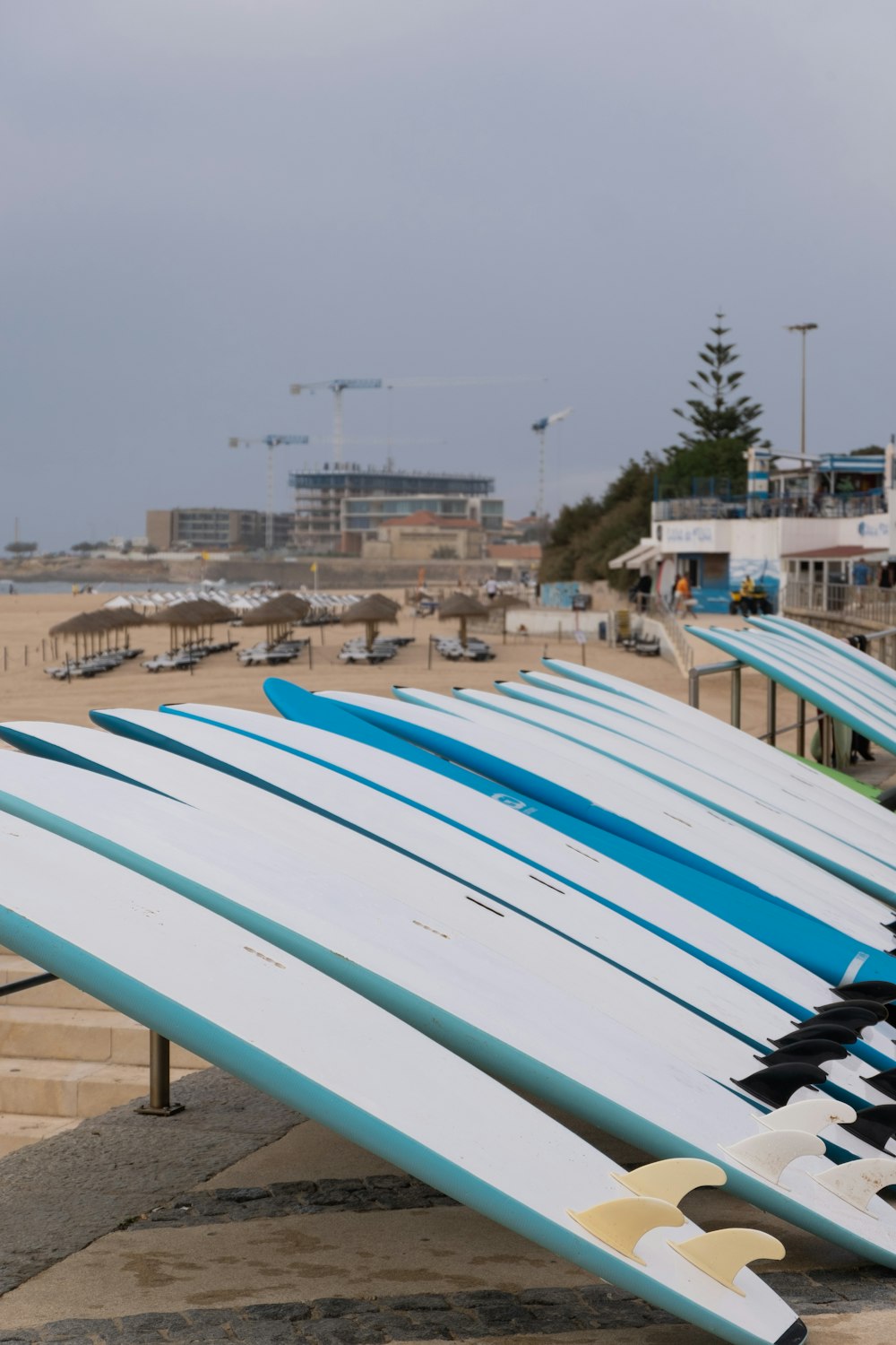 a row of surfboards sitting on top of a sandy beach