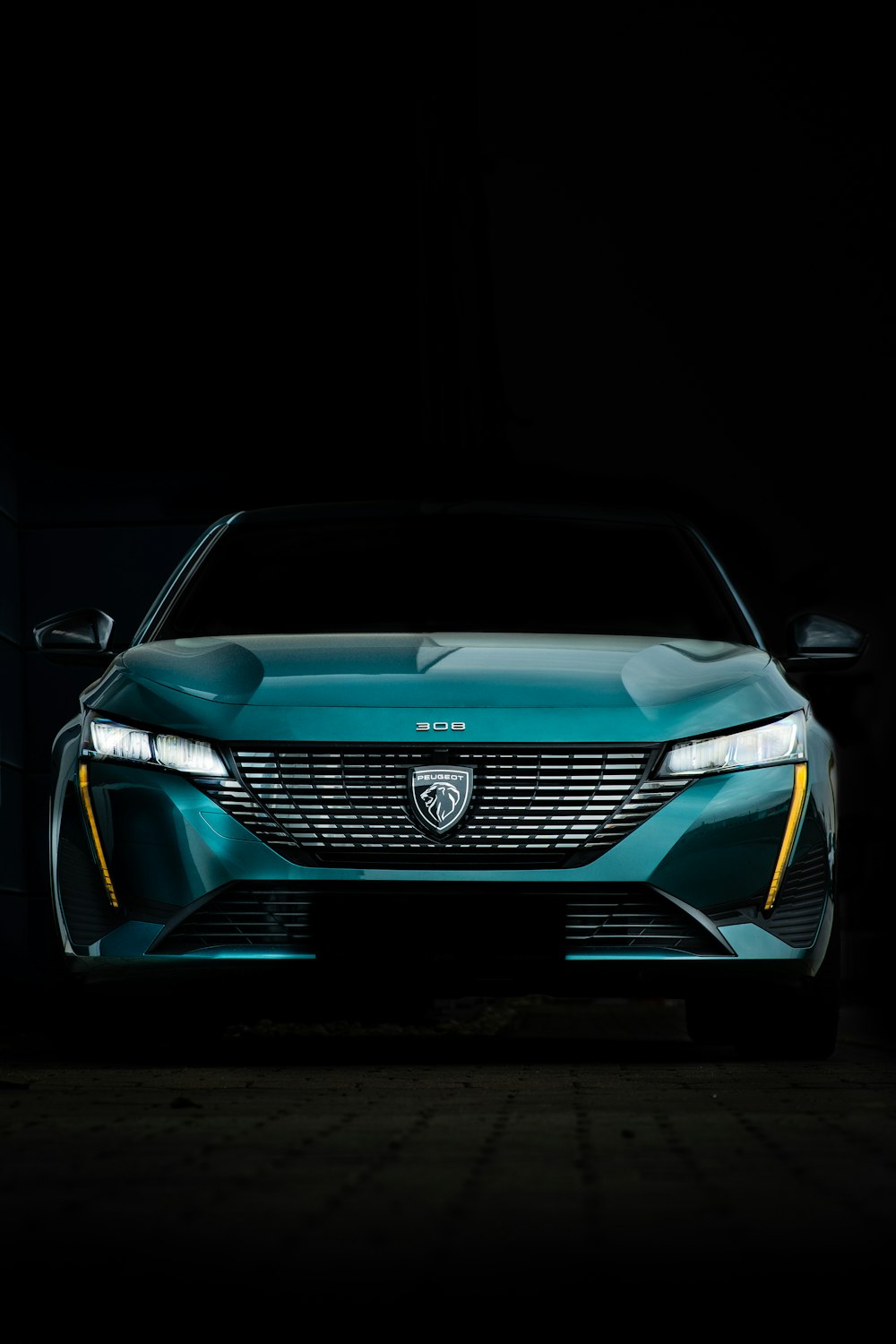 the front end of a blue car in a dark room