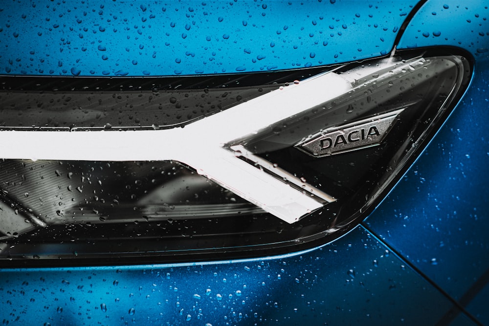 Un primer plano de un coche azul con gotas de lluvia