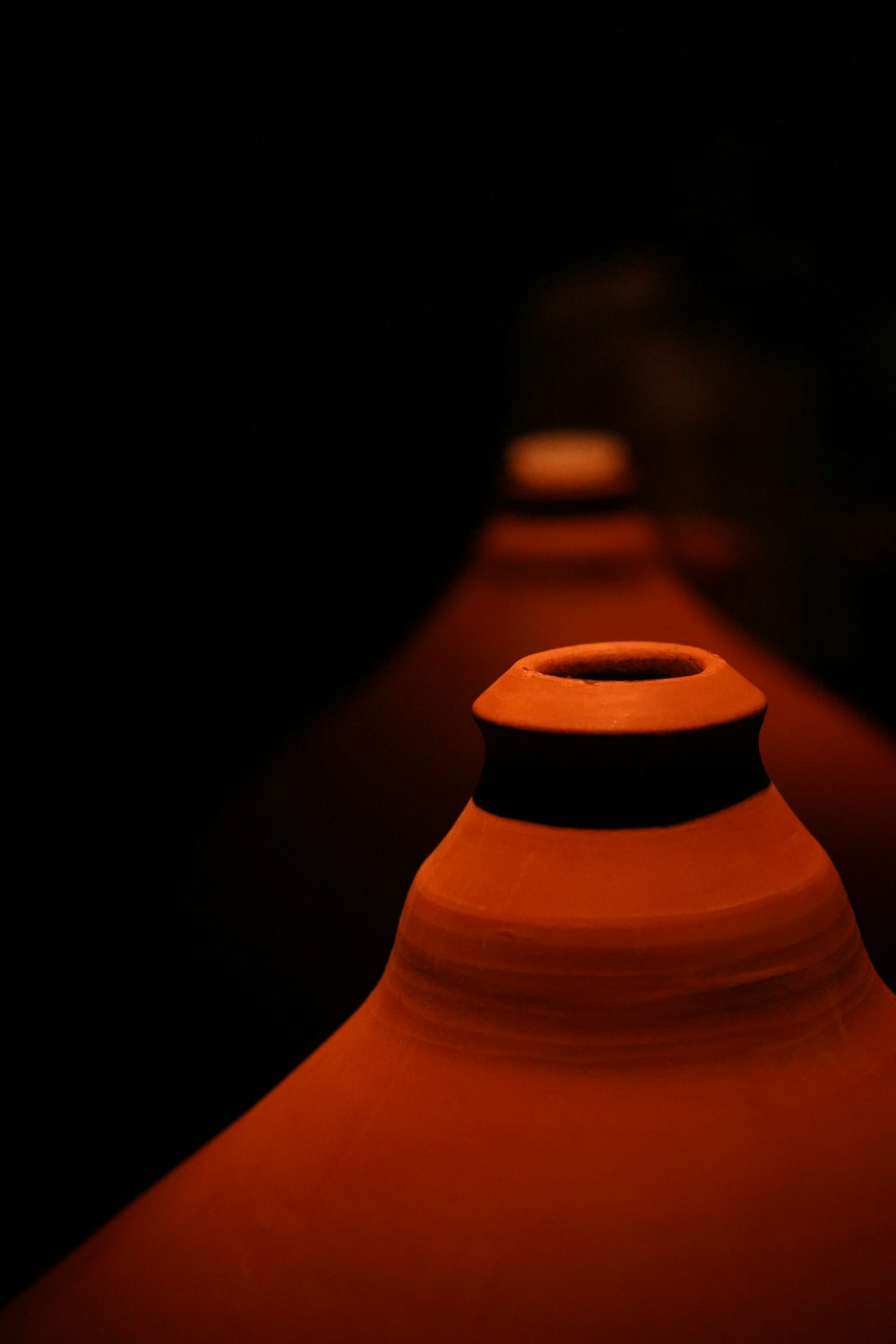 a row of red vases sitting on top of a table