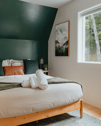 a bed with a white blanket and two folded towels on top of it