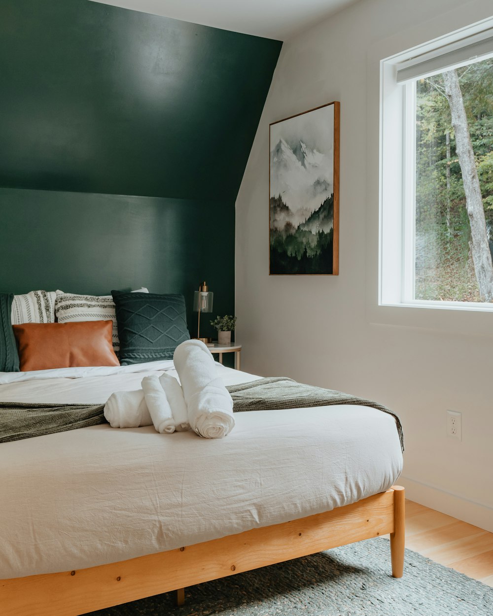 a bed with a white blanket and two folded towels on top of it