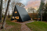 Black A-frame cabin against a pink dusk sky