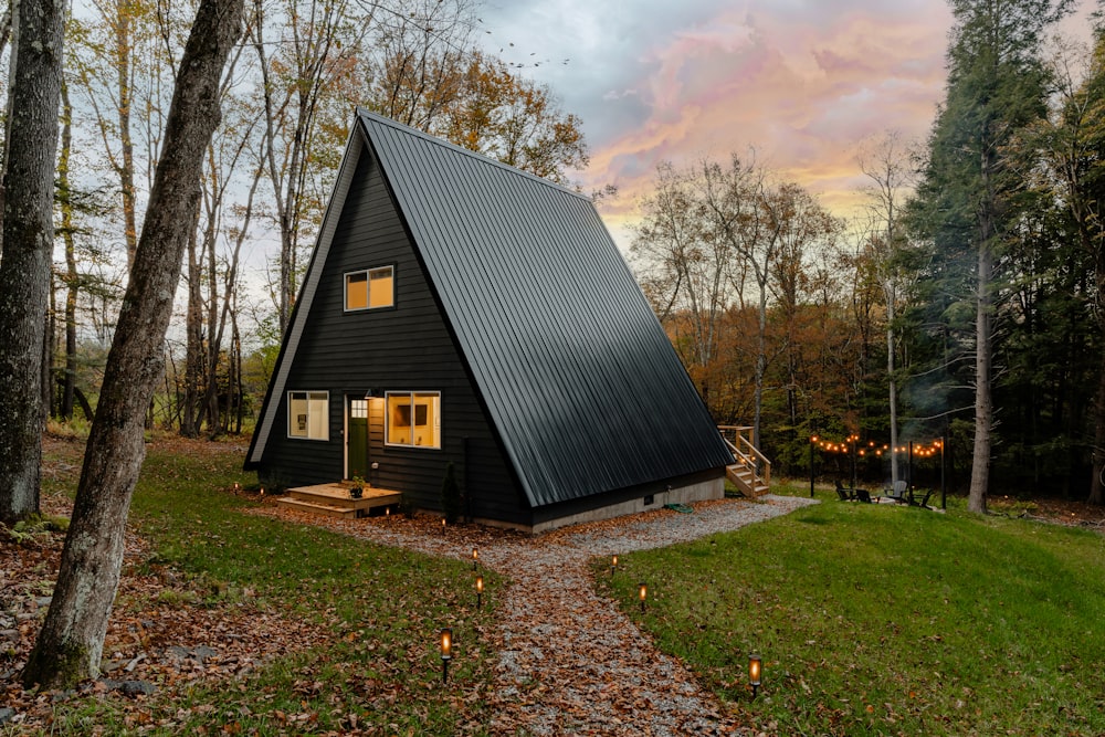 a small black cabin in the middle of a forest