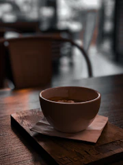 Cozy coffee shop corner with a steaming cup of coffee and rustic wooden furniture bathed in soft natural light