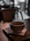 Cozy tea cup with steam rising, placed on a wooden table in a warm cafe setting.