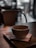 A steaming cup of coffee on a rustic wooden table surrounded by cozy seating and warm lighting.