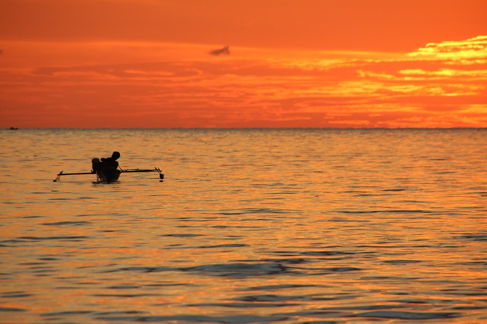 a person rowing a boat in the water at sunset