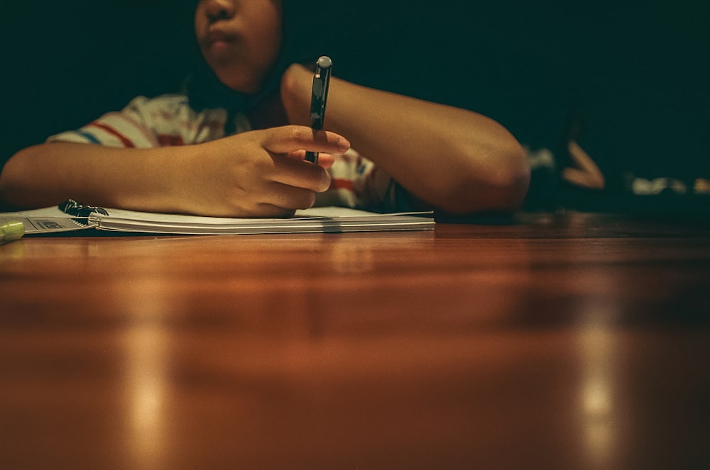 a person sitting at a table with a pen in their hand