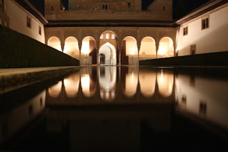 A warmly lit Moroccan riad courtyard with intricate tilework and lush greenery under a twilight sky.
