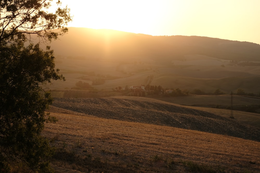 the sun is setting over the rolling hills
