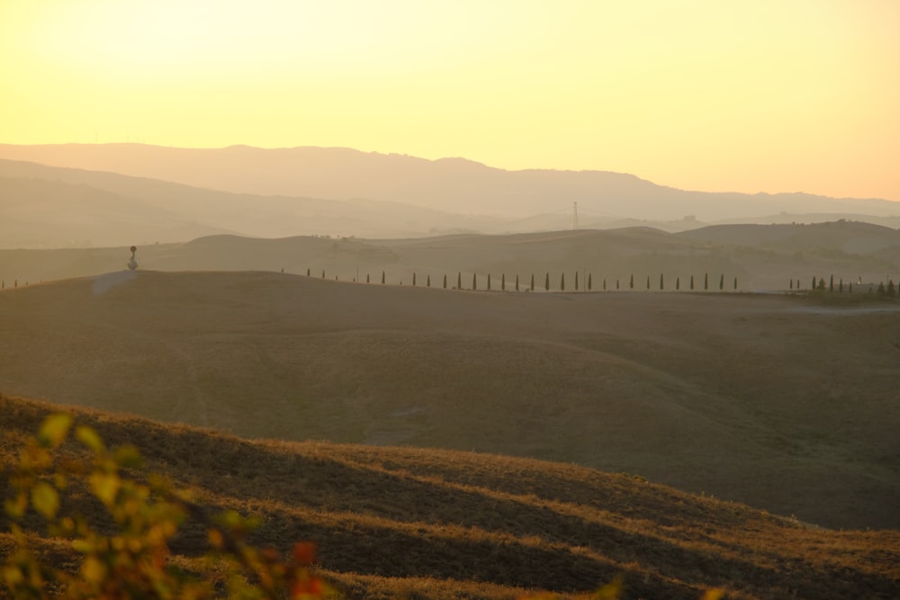 a field with hills in the background and a fence in the foreground