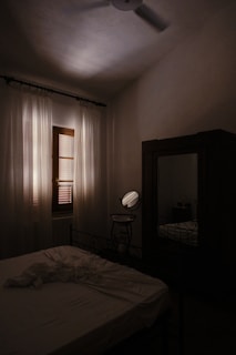 A softly lit bedroom with sheer curtains gently moving in a light breeze, creating a serene atmosphere.