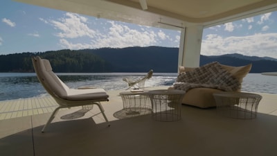A luxurious outdoor lounge area with natural wood furniture overlooking a calm lake.