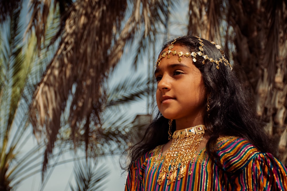 a young girl wearing a colorful dress and head piece