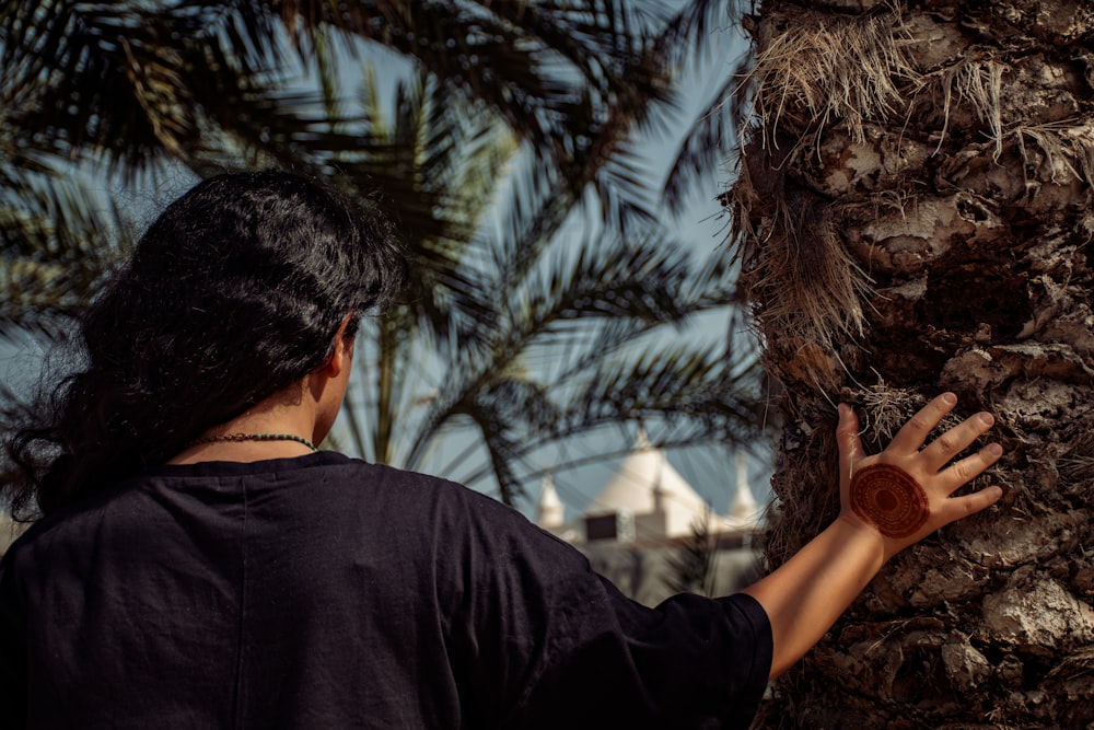 a woman reaching up to a palm tree