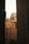 Tall building exteriors framed between two darkened towers, with a soft light casting warm tones on the architecture. The scene includes classic urban details like rooftop structures and numerous windows with air conditioning units.