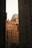 Tall building exteriors framed between two darkened towers, with a soft light casting warm tones on the architecture. The scene includes classic urban details like rooftop structures and numerous windows with air conditioning units.