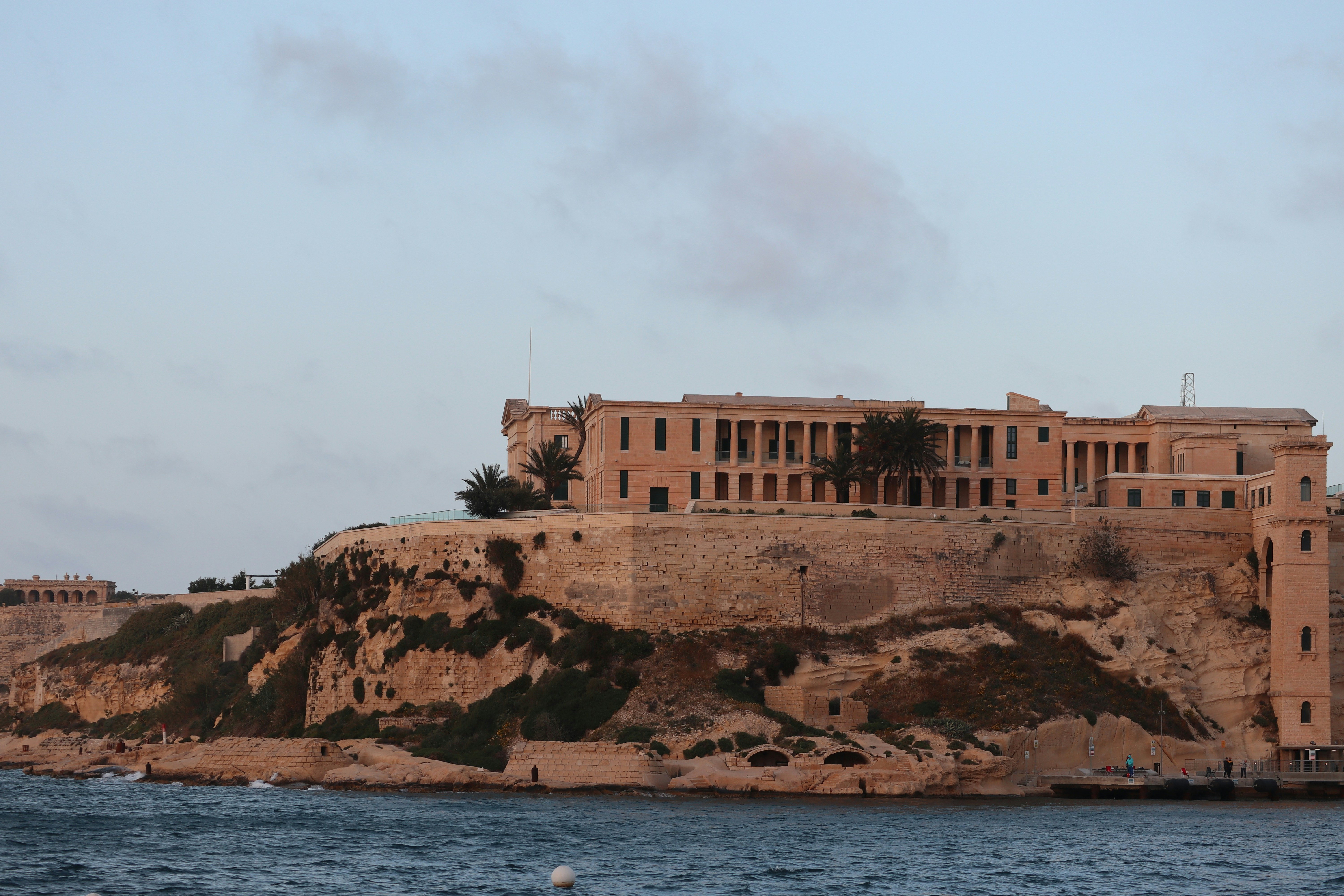 a large building sitting on top of a cliff next to a body of water