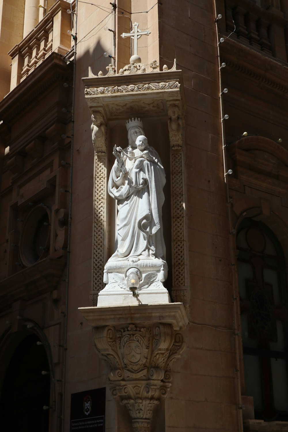 eine Statue eines Mannes, der ein Kreuz vor einem Gebäude hält