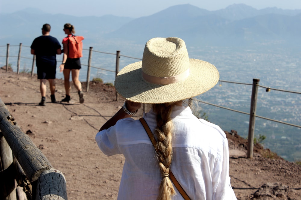 a woman wearing a hat standing on top of a hill