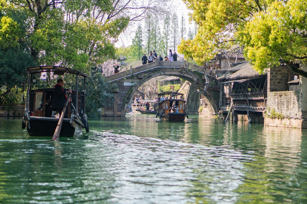 a boat traveling down a river next to a bridge