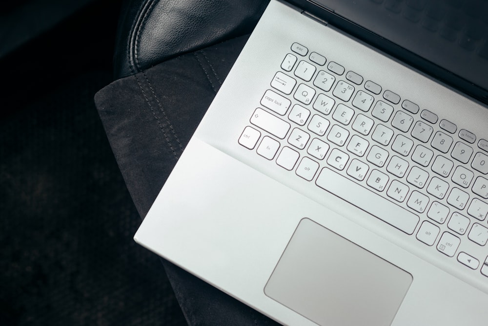 a laptop computer sitting on top of a black leather chair