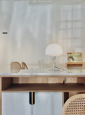 A sleek, minimalist office space with clean white surfaces and a glowing washed orange desk lamp.