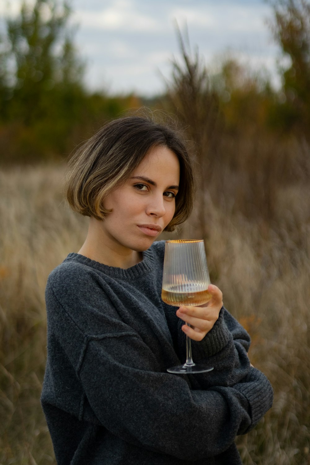 a woman holding a glass of wine in a field