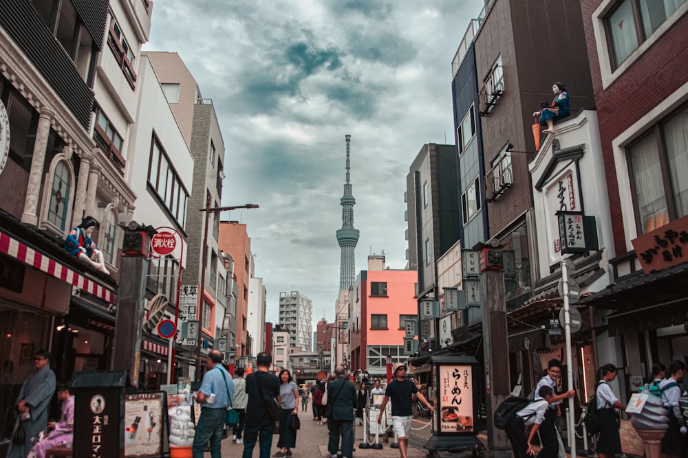 a group of people walking down a street next to tall buildings