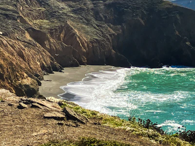 A serene coastal landscape with terracotta cliffs meeting the calm sea.