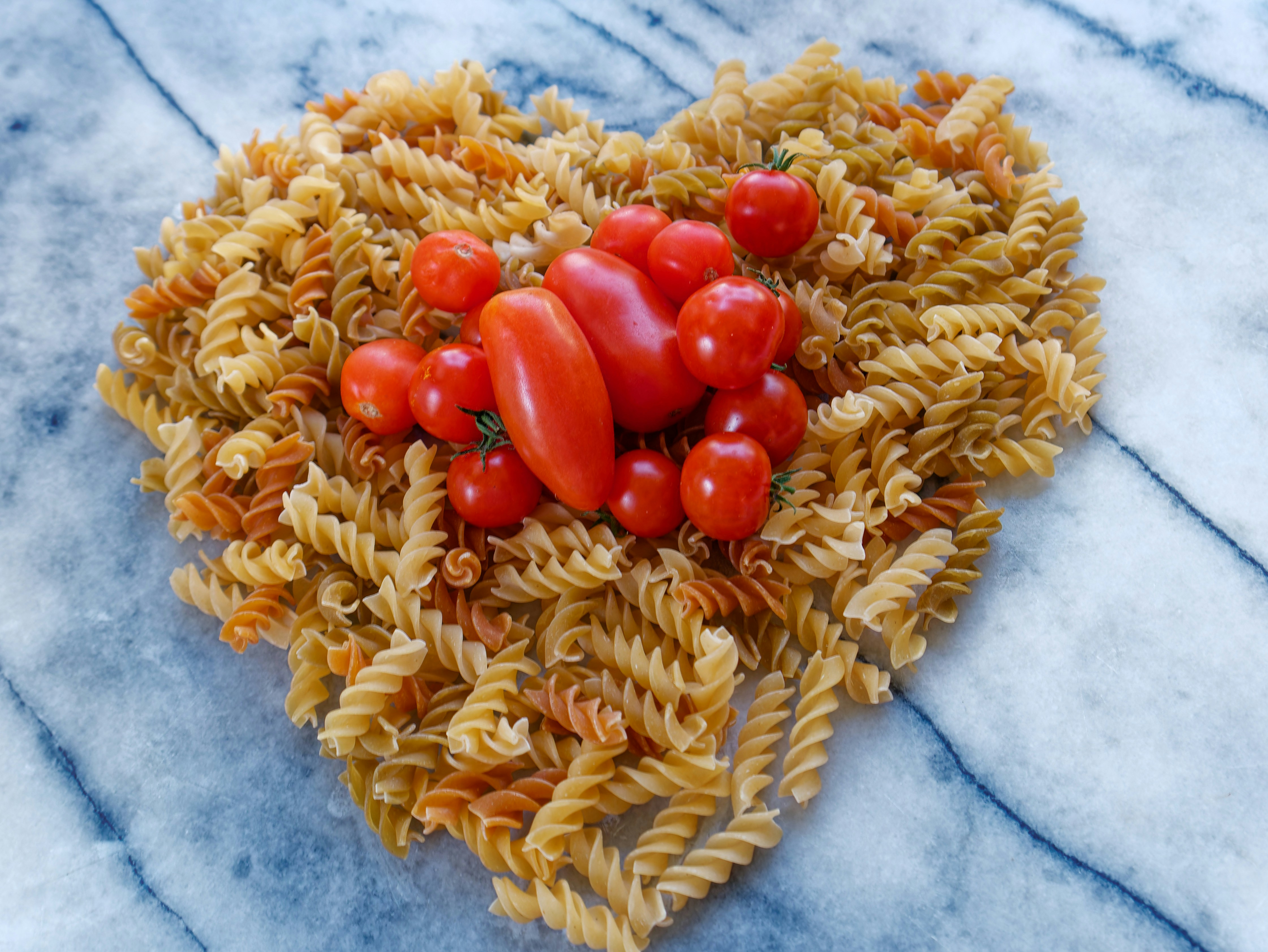 a heart shaped arrangement of pasta and tomatoes