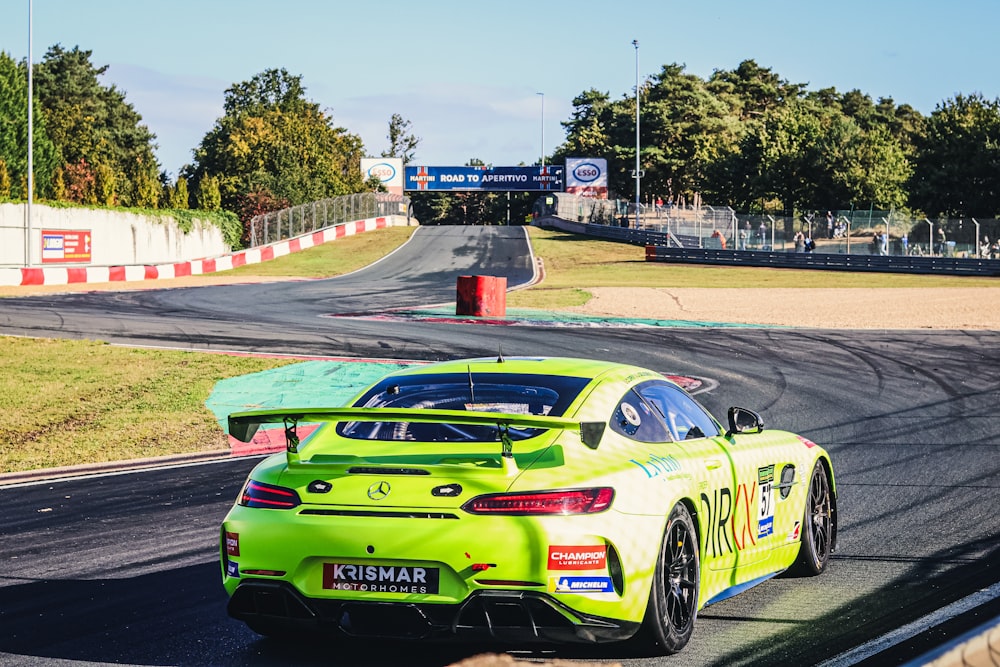 a green car driving down a race track