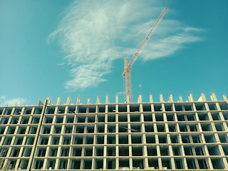 A close-up shot of skilled workers pouring concrete on a high-rise construction site under a clear sky.
