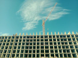 Steel framework of a high-rise residential building under construction against a clear sky.