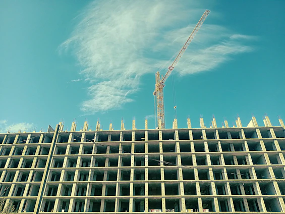 A close-up shot of skilled workers pouring concrete on a high-rise construction site under a clear sky.