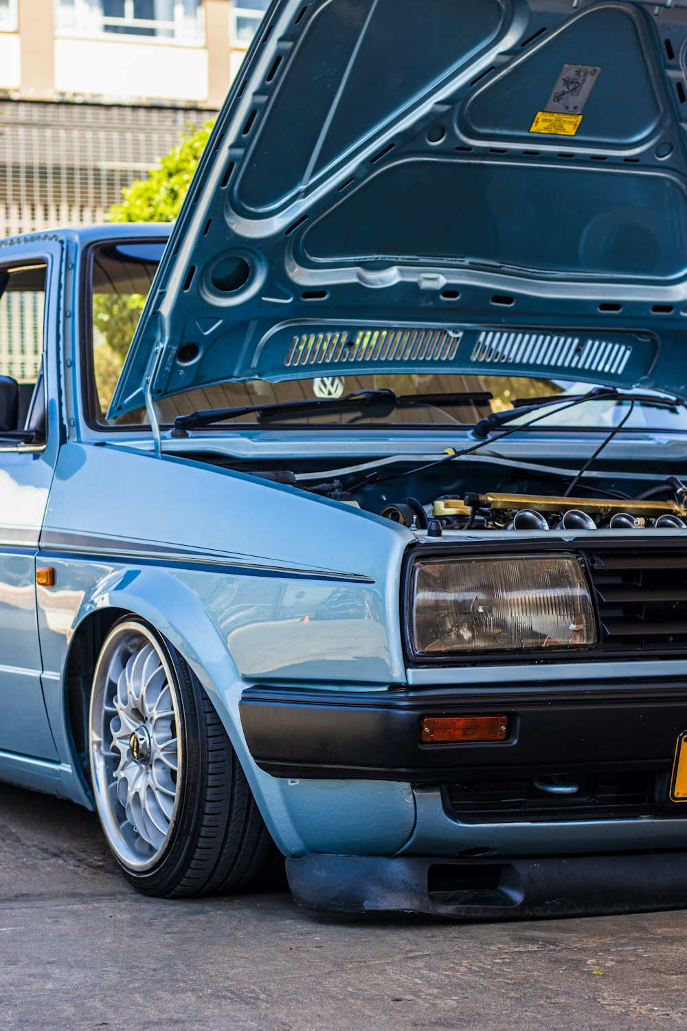 a blue car with its hood open in a parking lot