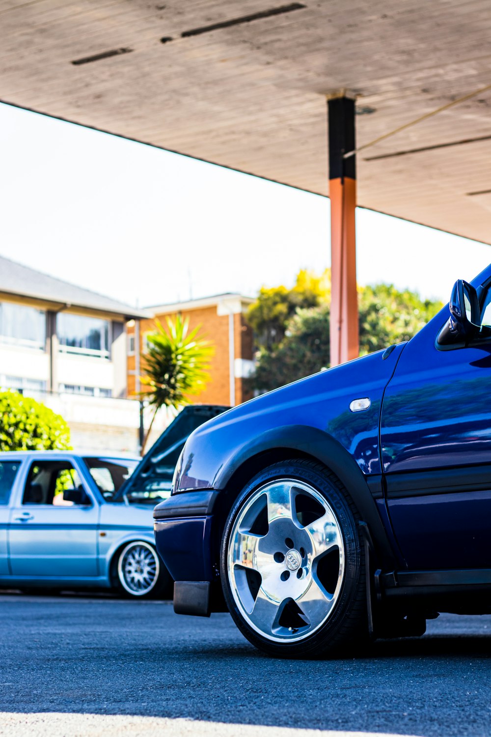 a blue car parked in a parking lot next to other cars