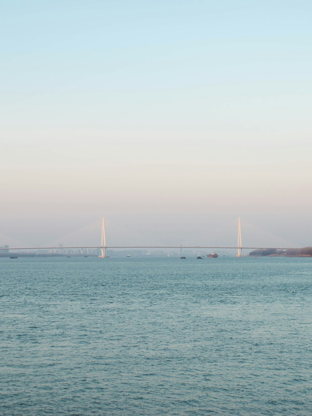 a large body of water with a bridge in the background