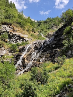 A cascading waterfall framed by lush greenery in the Ourika Valley under a bright blue sky