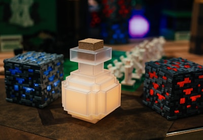 A collection of pixelated, Minecraft-themed objects, including a glowing potion bottle, blocks with blue and red accents, and various figurines resembling game elements.