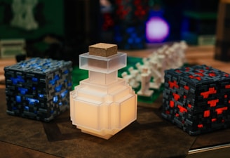 A collection of pixelated, Minecraft-themed objects, including a glowing potion bottle, blocks with blue and red accents, and various figurines resembling game elements.