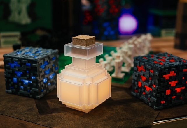 A collection of pixelated, Minecraft-themed objects, including a glowing potion bottle, blocks with blue and red accents, and various figurines resembling game elements.