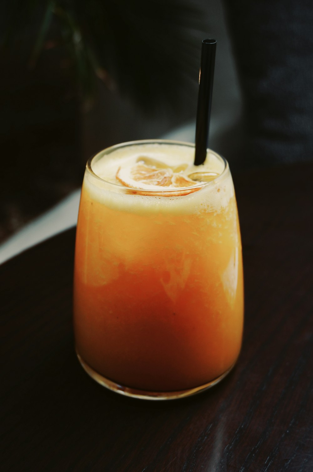 a glass of orange juice with a black straw