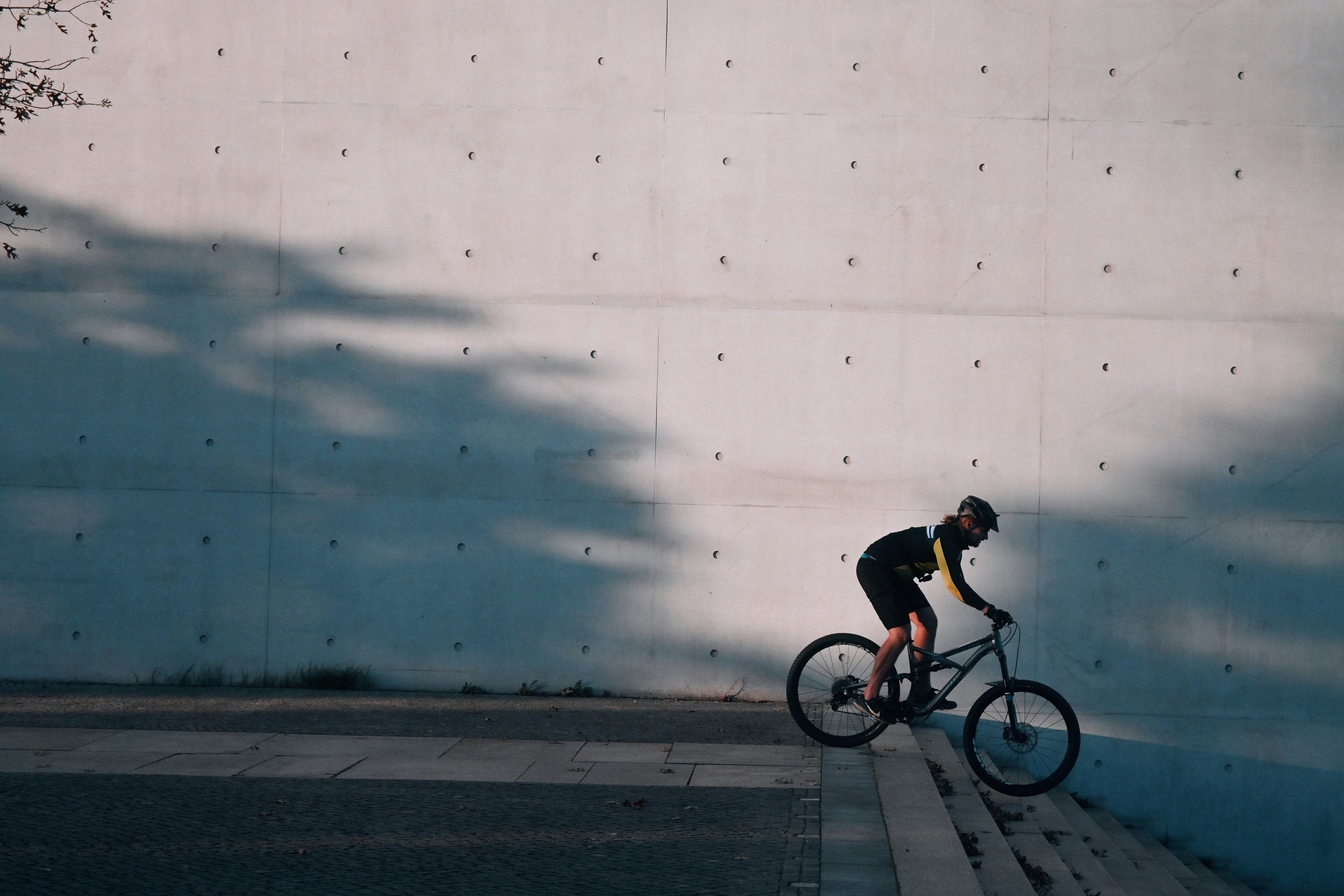 a man riding a bike down a street next to a wall