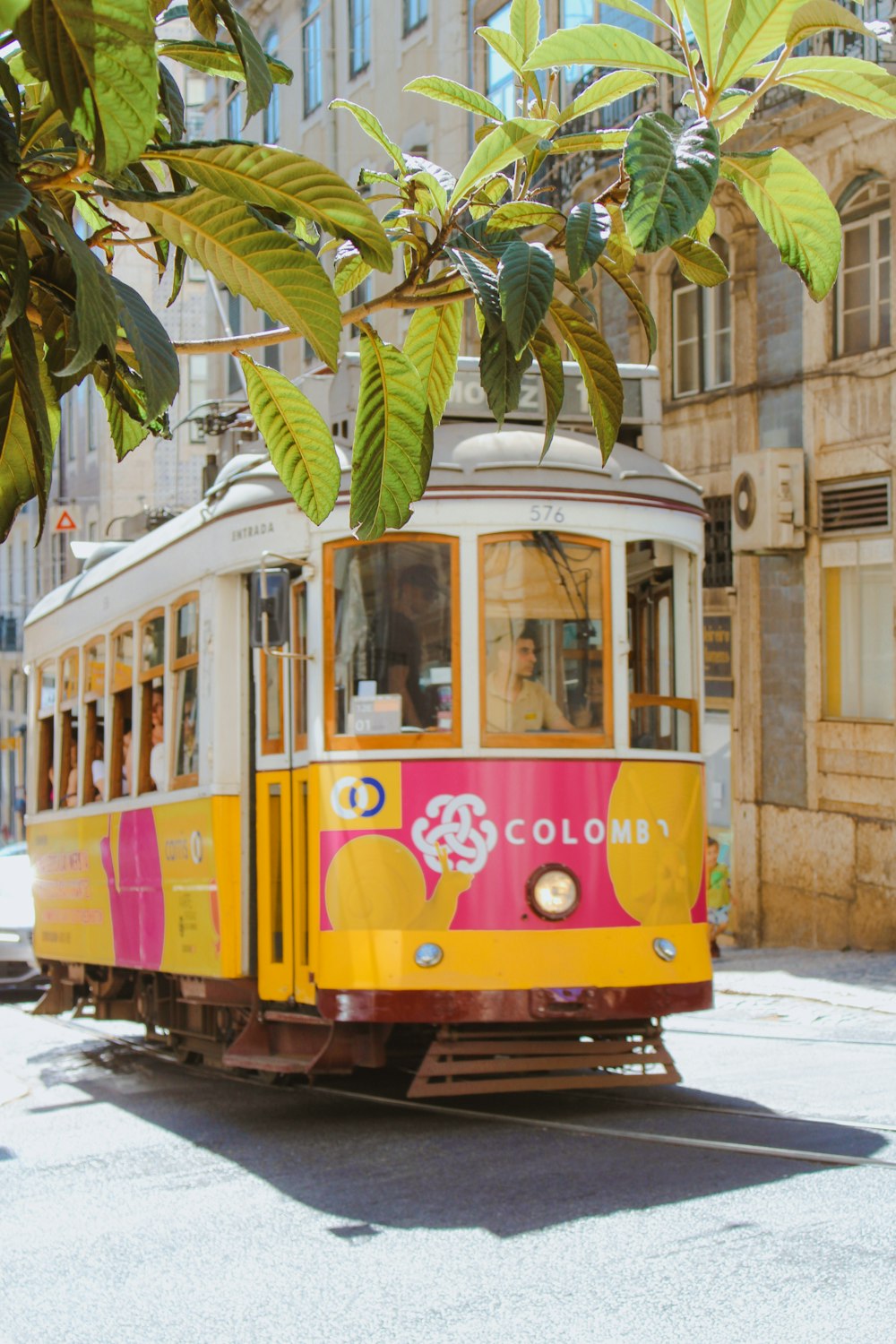 a yellow and pink trolley car on a city street