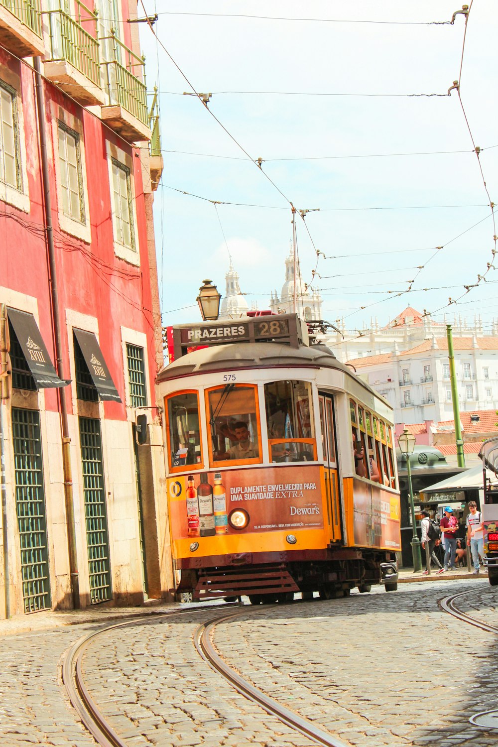 an orange trolley car traveling down a street next to a red building