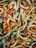 A pile of colorful gummy worms intertwined and overlapping each other, with vibrant shades of red, green, yellow, blue, and white.