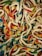 A pile of colorful gummy worms intertwined and overlapping each other, with vibrant shades of red, green, yellow, blue, and white.