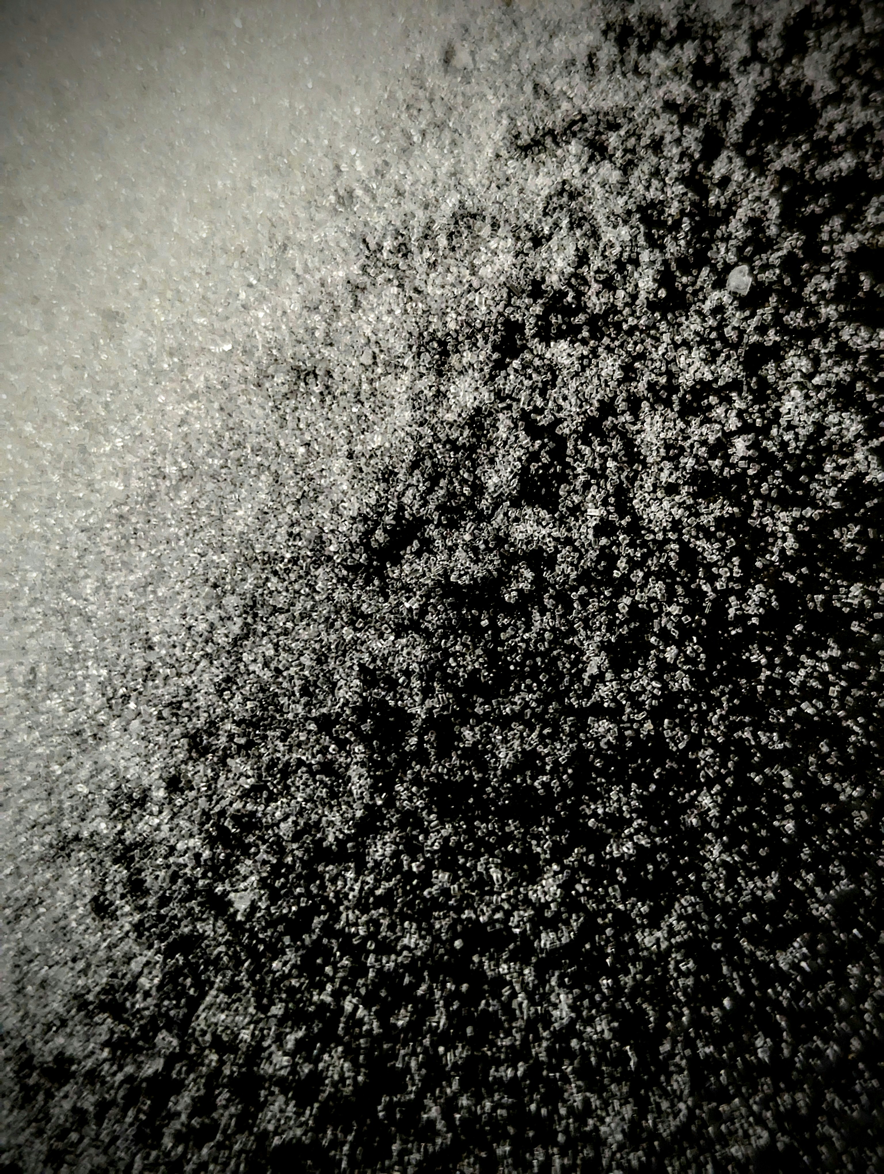 Crystalline sugar compound structures under bright overhead lab light, white surface